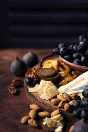 Tło do fotografii kulinarnej i produktowej Autumn Grapes. tło tylne to wzor o kolorze głębokiego fioletu. Na postawie tło brązowe Pumokin Spice. Kadr przestawia deskę serów z owocami, figami i winogronem. Piękny jesienny kadr