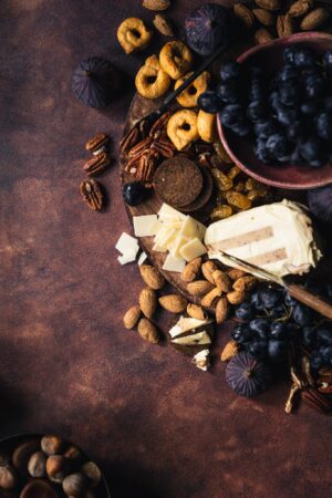 Tło do fotografii kulinarnej i produktowej Pumpkin Spice. Kadr przestawia deskę serów z owocami, figami i winogronem na brązowym , artystycznym tle z widoczną strukturą. Piękny jesienny kadr.